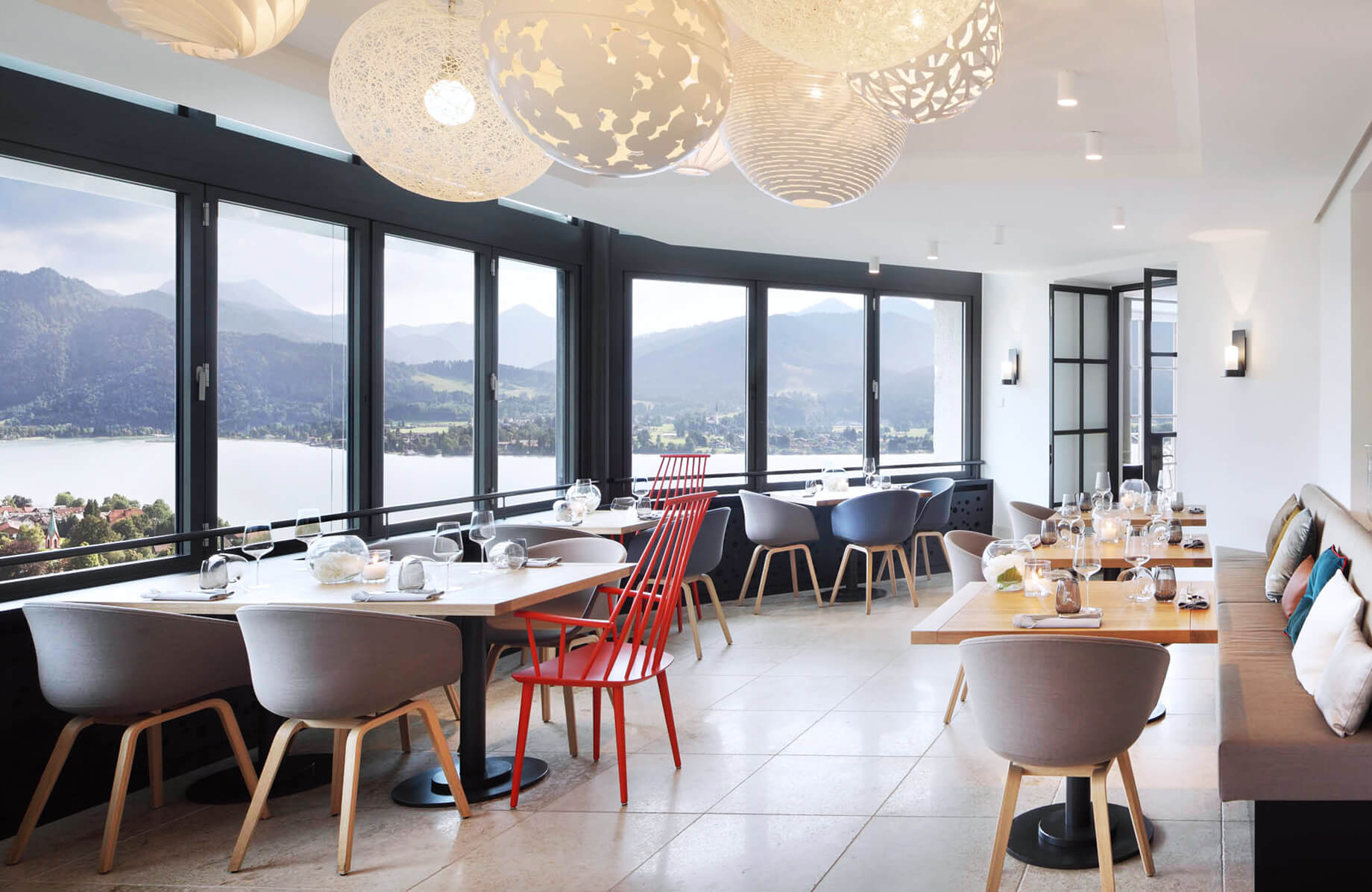 Aufnahme im Restaurant Alpenbrasserie am Tegernsee mit mehreren eingedeckten Tischen direkt an einer Fensterfront mit geöffneten Fenstern.