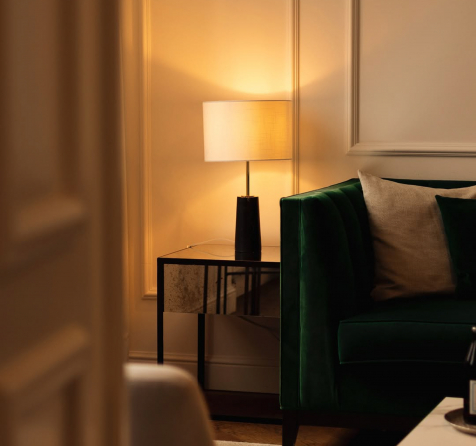 Einblick in ein Zimmer mit grüner Couch und stimmungsvoller Beleuchtung