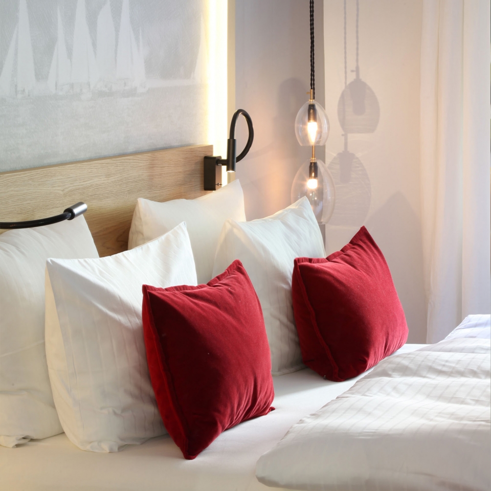 tailansicht eines Bettes mit gemütlichen Kissen und roten Details